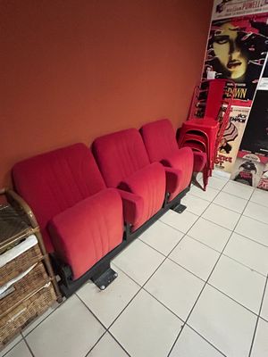 a red couch in the corner of a room with posters on the wall