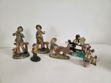five figurines of children and dogs on a white surface