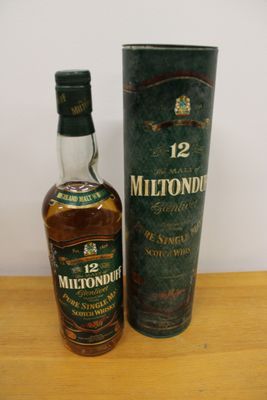 a bottle of whisky sitting next to a cardboard box on a table