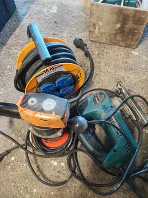 un tas d'outils électriques par terre, à côté d'une boîte
