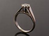 a close up of a ring with a diamond on a black surface