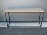 La table est en bois et en métal, avec un piètement noir.