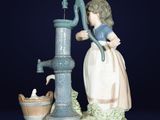 une figurine représentant une femme avec un seau et une pompe à eau