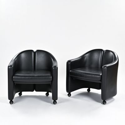 une paire de fauteuils de salon en cuir noir montés sur roulettes, sur fond blanc