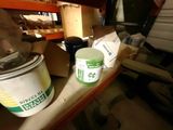un seau de peinture posé sur une étagère à côté d'un pot de peinture