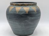 un vase bleu et brun posé sur une surface blanche