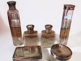 four glass bottles and a silver container on a white surface