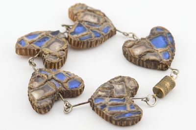 quatre perles de verre bleues et marron en forme de cœur sur un fond blanc