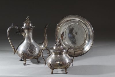 deux théières en argent et une assiette en argent posées sur une table