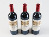 three bottles of red wine sitting next to each other on a white surface