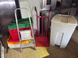 a red hand truck and a white trash can next to each other