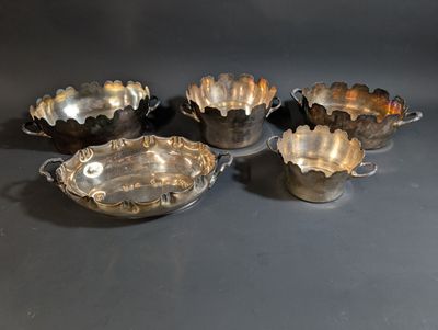 four silver plated bowls with handles and handles on a black surface