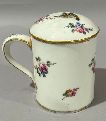 une tasse blanche bordée d'or et ornée d'un motif floral