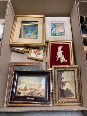 une boîte remplie d'œuvres d'art encadrées posée par terre