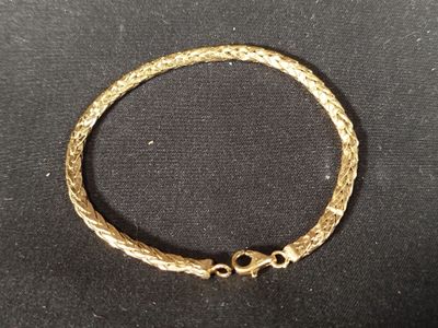 gros plan d'un bracelet en or sur une surface noire