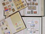 trois livres ouverts, sur lesquels sont apposés des timbres, posés sur une table