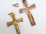 two cross pendants on a white surface with a gold chain