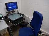 un bureau d'ordinateur avec une chaise bleue et un écran posé dessus