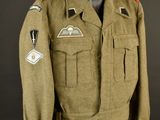 une veste d'uniforme militaire ornée d'écussons, posée sur un mannequin