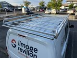 a white van parked in a parking lot with a roof rack on it
