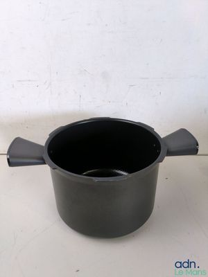 un pot noir muni d'une anse, posé sur une table blanche