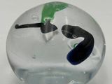 a glass ball with a face and a green leaf on it