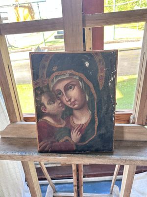 tableau représentant la Vierge à l'Enfant sur un chevalet en bois devant une fenêtre