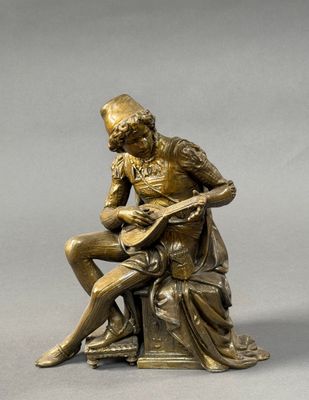 bronze statue of a man sitting on a rock playing a guitar