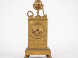 une horloge en or surmontée d'un globe terrestre
