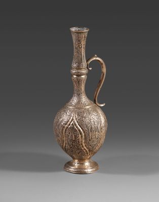 un vieux vase en argent muni d'une anse, sur un fond gris