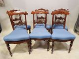 quatre chaises anciennes aux assises rembourrées de bleu dans une pièce