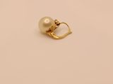 a gold pearl and diamond ring on a beige background