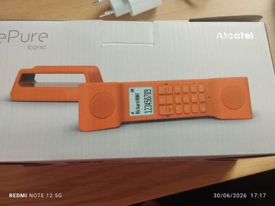 un téléphone portable orange posé sur une boîte, sur une table