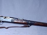 un fusil sur fond blanc, avec une crosse marron et un étui vert