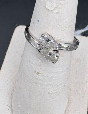 a silver ring with a diamond on it sitting on a ring stand