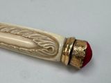 a white and gold pen with a red ball on it