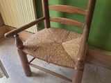 a wooden chair with a woven seat in front of a green wall
