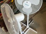 a white fan sitting on top of a stand in a garage