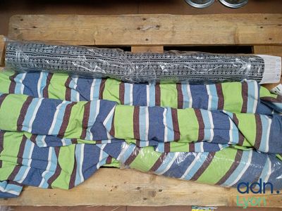 un tas de vêtements posé sur une palette, à côté d'une paire de ciseaux