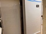 a refrigerator in the corner of a room next to a toilet