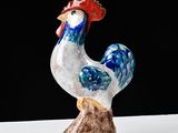 rooster figurine on a white surface against a black background
