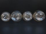 four empty wine glasses lined up on a black surface