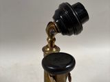a small brass object with a black knob on it
