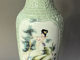 a green vase with a picture of a woman on it
