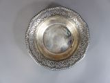 une assiette en argent posée sur une table blanche, sur fond noir