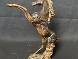 a bronze statue of a horse on a rock on a black background