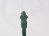 a green statue of a woman sitting on a plate with her hands on her face