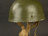an old green helmet on a metal stand against a black background