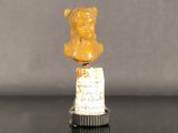 une petite statuette représentant un ours en peluche posée sur une bouteille