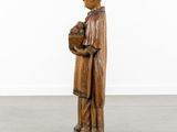 a wooden statue of a man holding a basket of fruit